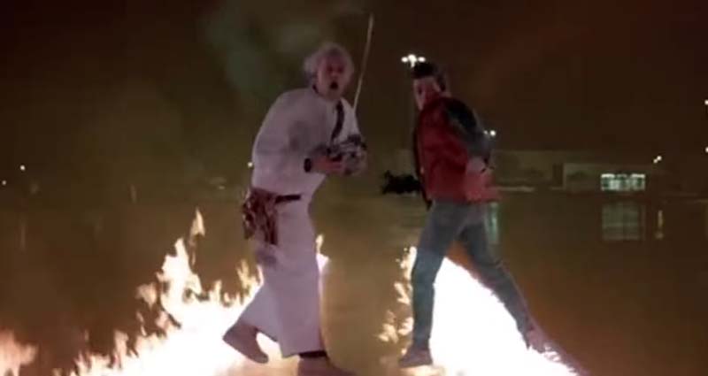A scene from Back to the Future with two men standing on flaming tire tracks.